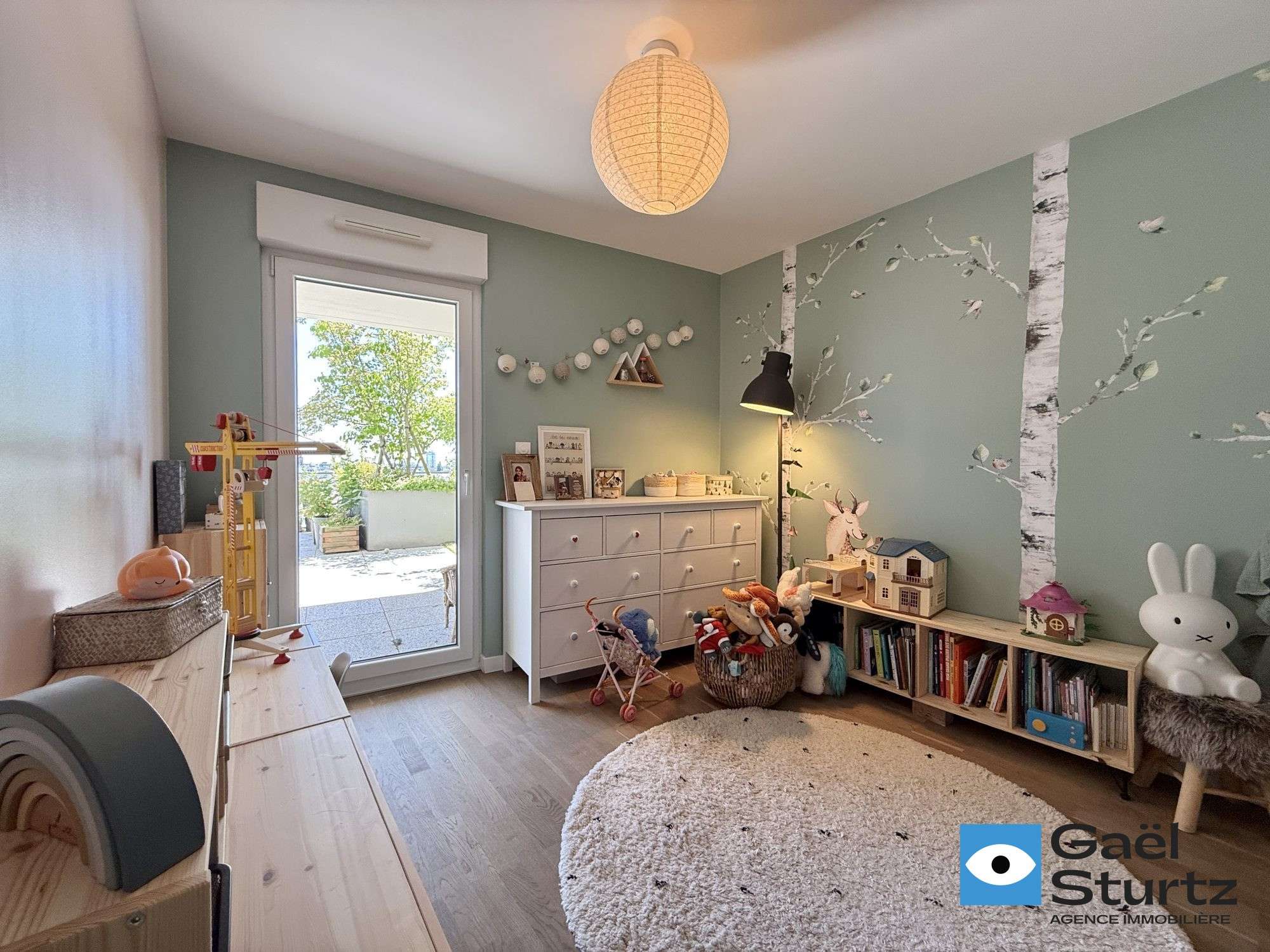 Chambre actuellement aménagée pour un enfant, avec accès vitré extérieur.