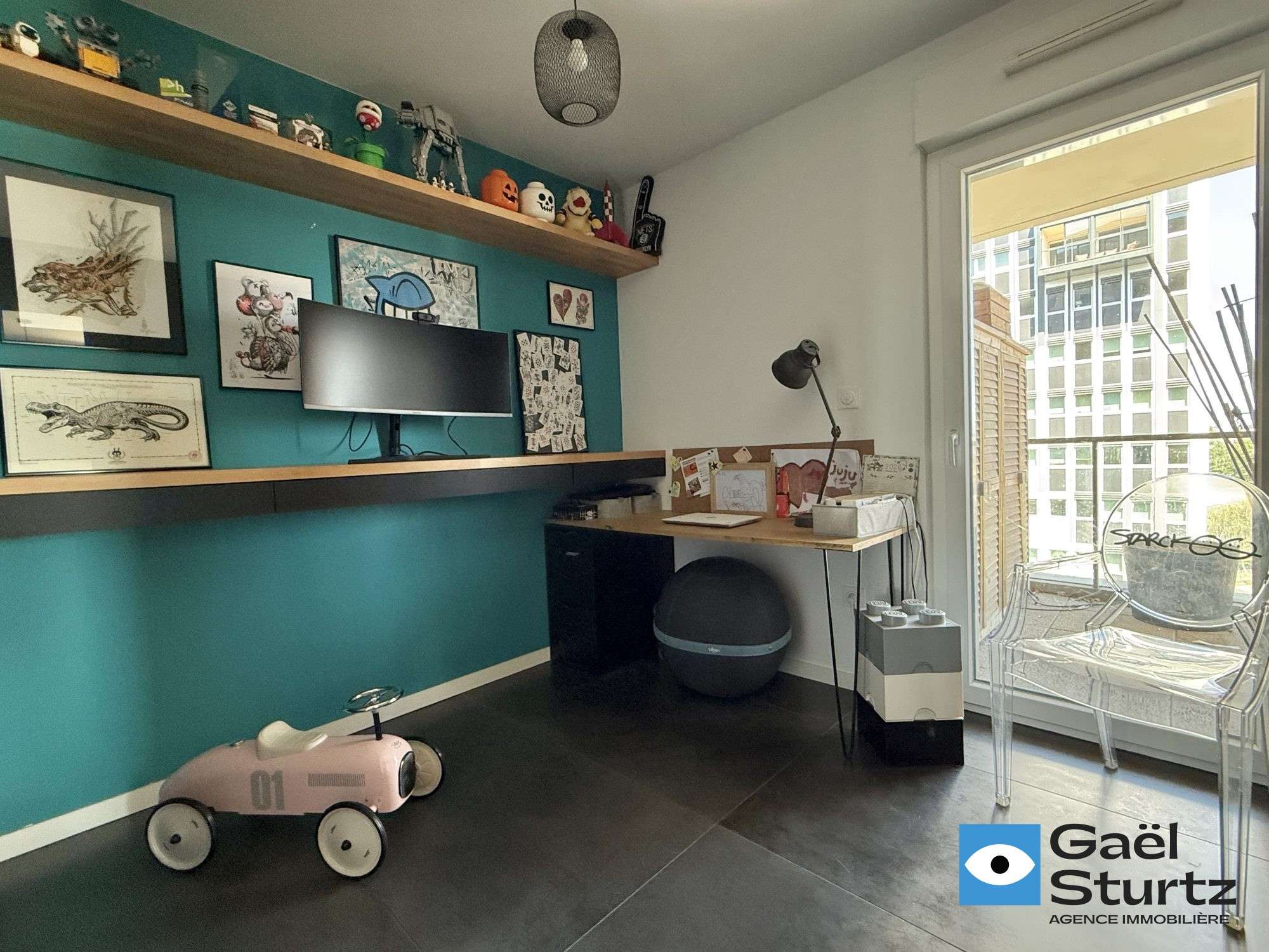 Troisième chambre actuellement utilisée en bureau, avec espace de travail et mur vert.