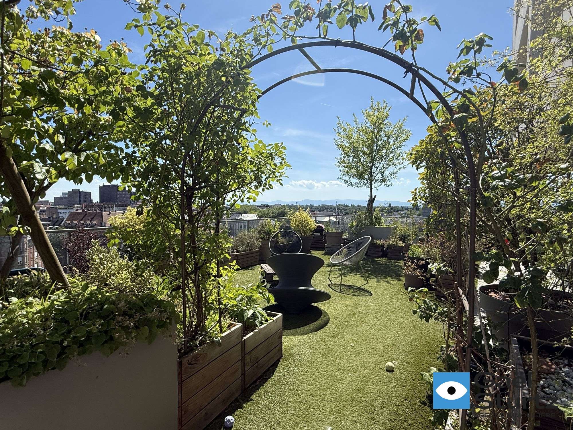 Arche végétalisée, arbustes et assises sur la terrasse.